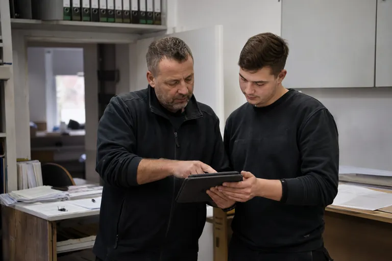 Ausbilder und Auszubildender prüfen auf einem Tablet die Vollständigkeit von Ausbildungsnachweisen