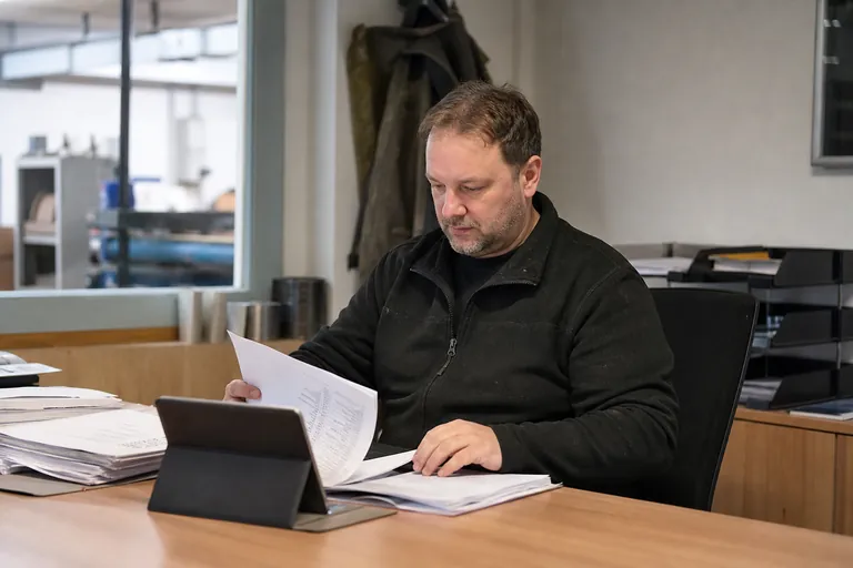 Ausbilder ordnet Ausbildungsunterlagen und ein Tablet auf einem Schreibtisch